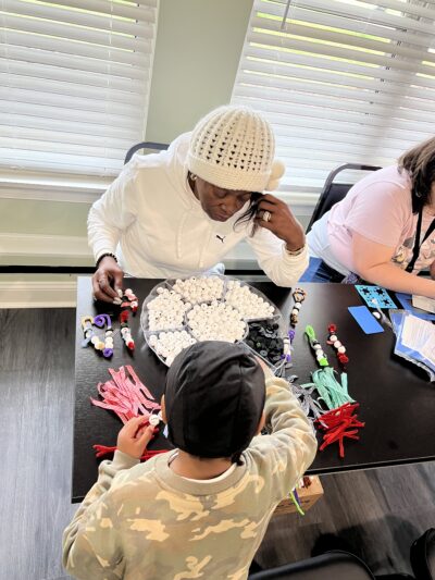 Two people building snowmen with pipe cleaners and beads